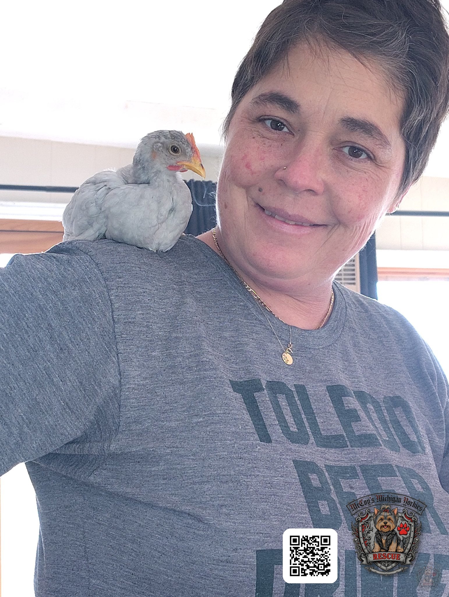 Crystal smiling with a young white chicken perched on her shoulder