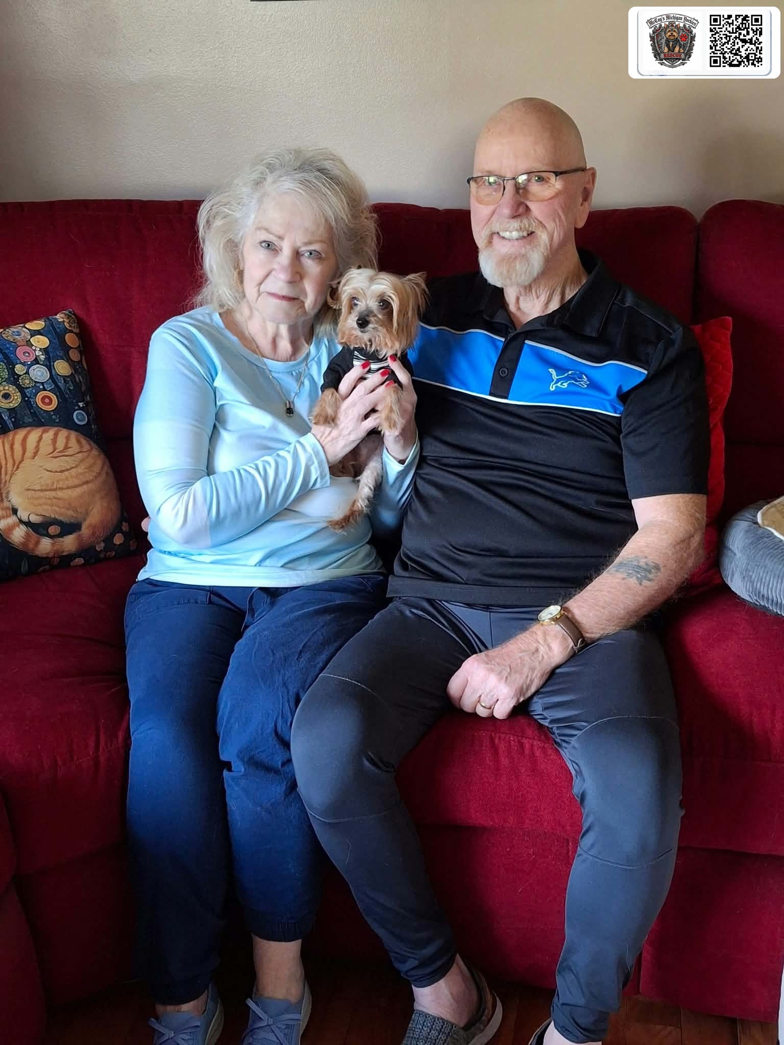Cal and Darlene smiling on their couch while holding Sawyer, their senior rescue Yorkshire Terrier